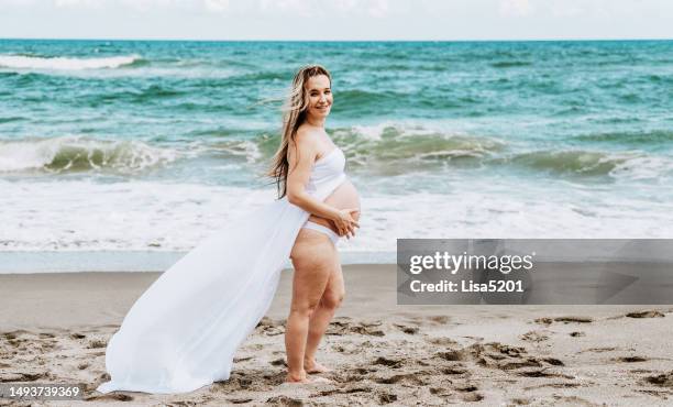 beautiful pregnant woman with exposed belly in flowing dress in an idyllic beach location, hope anticipation and new life - beautiful perfection exposed lady stock pictures, royalty-free photos & images