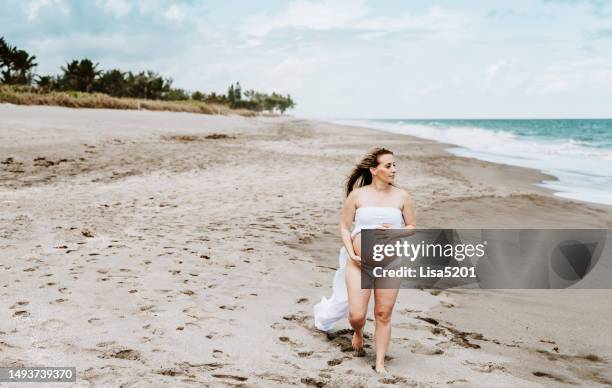 beautiful pregnant woman with exposed belly in flowing dress in an idyllic beach location, hope anticipation and new life - beautiful perfection exposed lady imagens e fotografias de stock