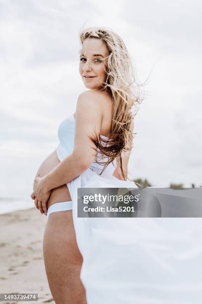 beautiful pregnant woman with exposed belly in flowing dress in an idyllic beach location, hope anticipation and new life - beautiful perfection exposed lady stock pictures, royalty-free photos & images