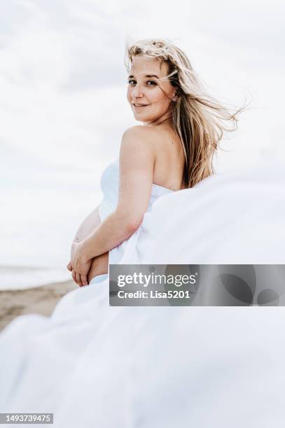 beautiful pregnant woman with exposed belly in flowing dress in an idyllic beach location, hope anticipation and new life - beautiful perfection exposed lady stock pictures, royalty-free photos & images