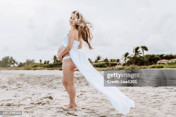 beautiful pregnant woman with exposed belly in flowing dress in an idyllic beach location, hope anticipation and new life - beautiful perfection exposed lady bildbanksfoton och bilder