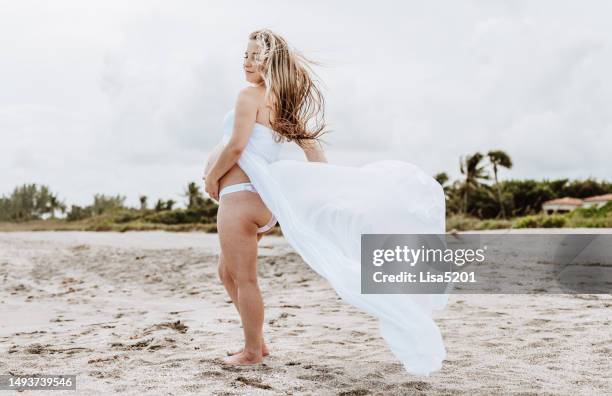 beautiful pregnant woman with exposed belly in flowing dress in an idyllic beach location, hope anticipation and new life - beautiful perfection exposed lady stock pictures, royalty-free photos & images