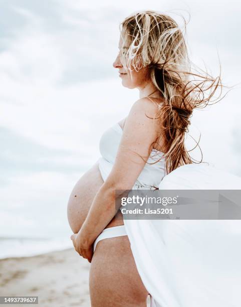 beautiful pregnant woman with exposed belly in flowing dress in an idyllic beach location, hope anticipation and new life - beautiful perfection exposed lady stock pictures, royalty-free photos & images