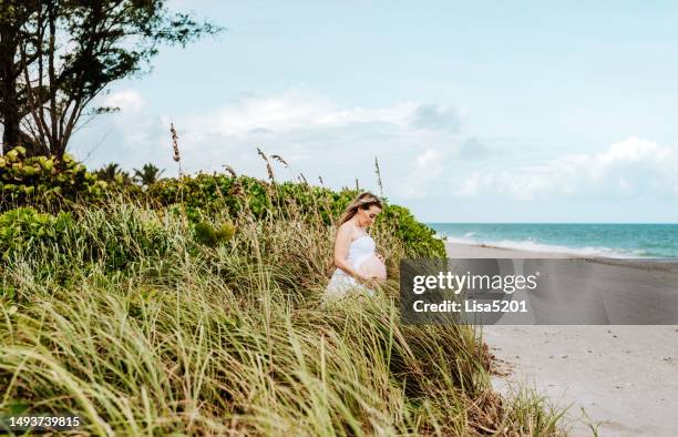 beautiful pregnant woman with exposed belly in flowing dress in an idyllic beach location, hope anticipation and new life - beautiful perfection exposed lady stock pictures, royalty-free photos & images