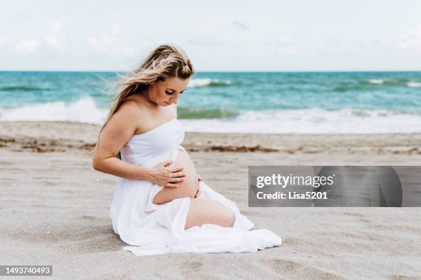 schöne schwangere frau mit entblößtem bauch in fließendem kleid in idyllischer strandlage, hoffnung vorfreude und neues leben - beautiful perfection exposed lady stock-fotos und bilder