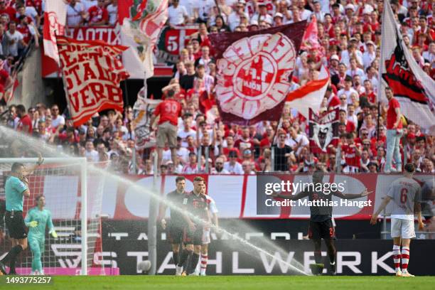 Dayot Upamecano of FC Bayern Munich reacts as the pitch water sprinkler is turned on during the Bundesliga match between 1. FC Köln and FC Bayern...