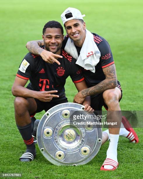 Serge Gnabry and Joao Cancelo of FC Bayern Munich pose for a photo with the Bundesliga Meisterschale trophy after the team's victory in the...