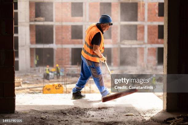 construction worker using broom to clean the dust on construction site - cleaning in progress stock pictures, royalty-free photos & images