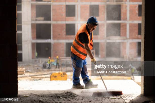 bauarbeiter mit besen zur reinigung des staubs auf der baustelle - city cleaning stock-fotos und bilder