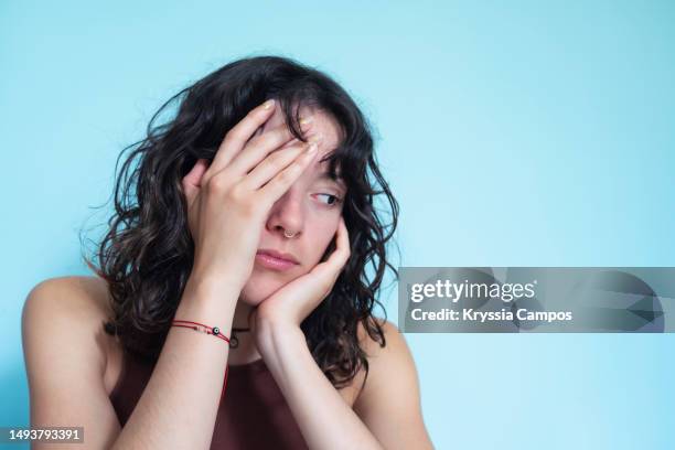 unhappy young woman covering her face with one hand looking down. copy space - negatieve eigenwaarde stockfoto's en -beelden