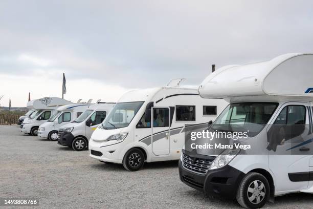 group of white motorhomes parked in the parking lot of a campsite. - camper foto e immagini stock