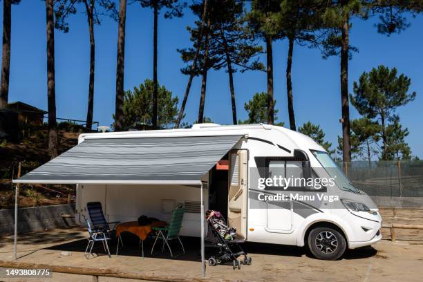 motorhome parked in a parking lot in the woods with the awning extended on a sunny holiday day. - trailer park imagens e fotografias de stock