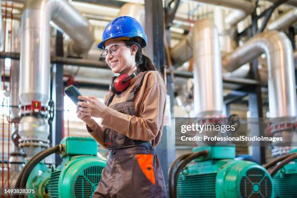 young woman sends updates on plant status with her phone - district heating plant 個照片及圖片檔