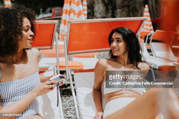 two woman on adjacent sun loungers talk to each other. - beautiful woman candid face 個照片及圖片檔