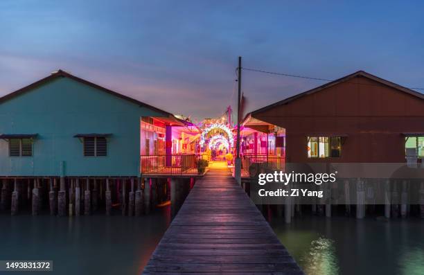 neon lights at lee jetty at sunset - clan jetties floating village of penang, malaysia - georgetown world heritage building stockfoto's en -beelden