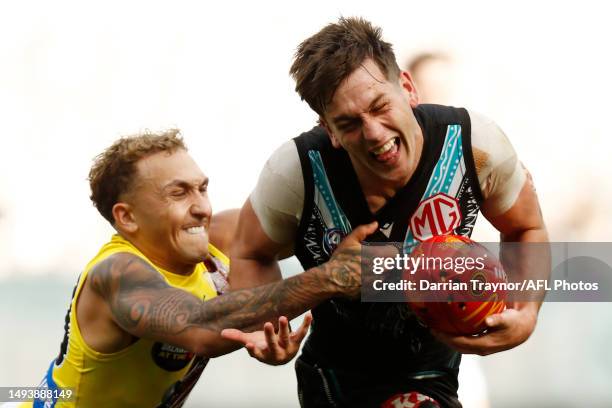 Zak Butters of the Power evades the tackle of Shai Bolton of the Tigers during the round 11 AFL match between Richmond Tigers and Yartapuulti / Port...