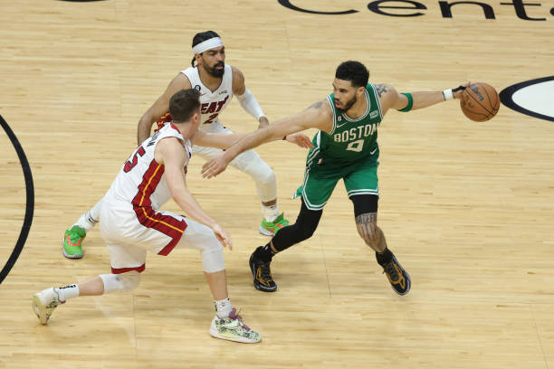 Jayson Tatum of the Boston Celtics controls the ball ahead of Duncan Robinson and Gabe Vincent of the Miami Heat during the fourth quarter in game...