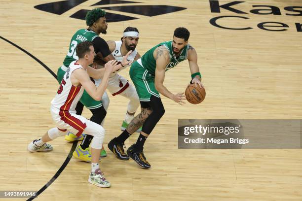 Jayson Tatum of the Boston Celtics controls the ball ahead of Duncan Robinson and Gabe Vincent of the Miami Heat during the fourth quarter in game...