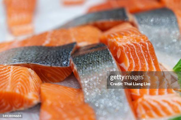 nahaufnahme von frischem rohem lachs, fischfilets und steaks, die auf zerstoßenem eis im einzelhandel präsentiert werden. - salmon steak stock-fotos und bilder