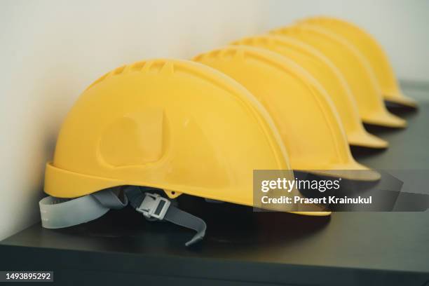 yellow safety helmet on table - workers compensation stock pictures, royalty-free photos & images