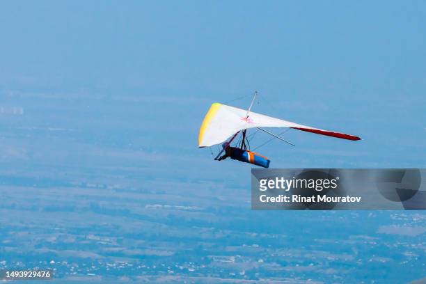 low angle photo of hang glider flying in clear bright sky - hang glider stock pictures, royalty-free photos & images