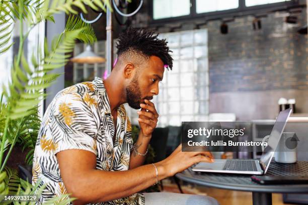 young editor of west asian ethnicity using laptop displaying doubt and concern regarding hard decisions at cafe - tough decisions stock pictures, royalty-free photos & images