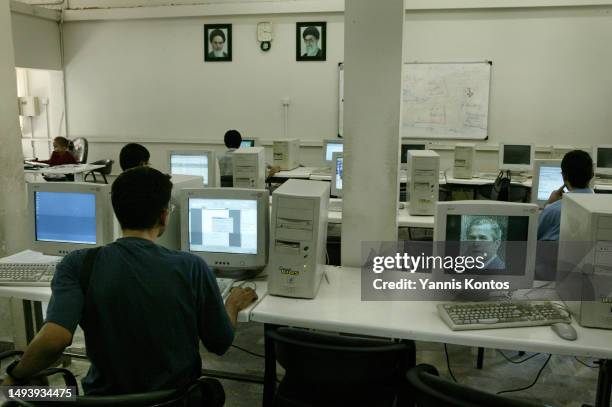 Iranian students work in computer tasks as a pixelated image of U.S. President George W. Bush appears on a screensaver, at the University of Tehran,...