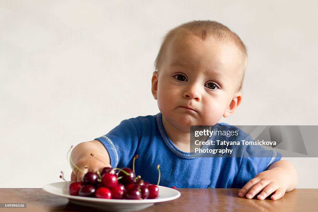 Portrait of baby boy eating cherries