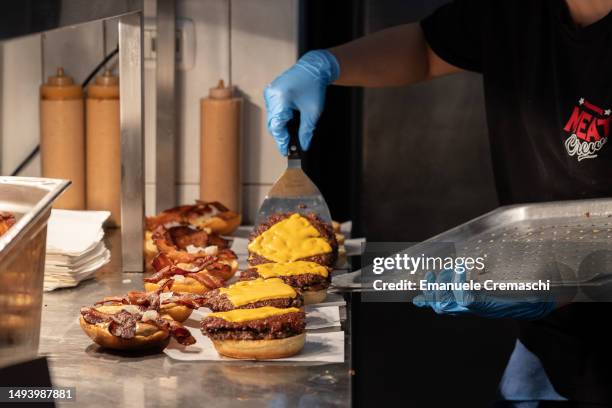 An employee prepares some bacon cheeseburgers at Meat Crew fast food restaurant on May 28, 2023 in Milan, Italy. On occasion of the World Burger Day,...