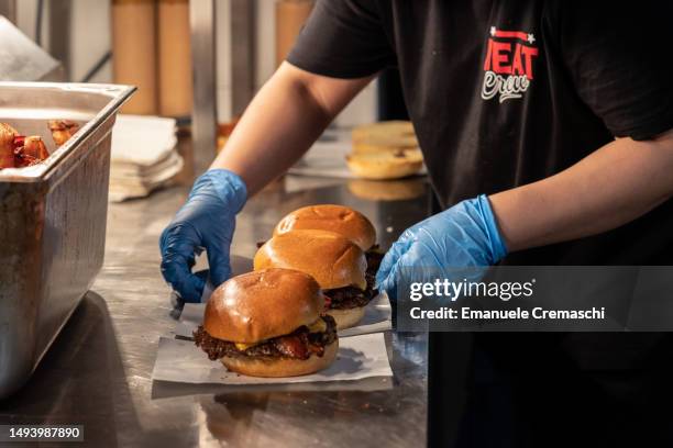 An employee prepares some bacon cheeseburgers at Meat Crew fast food restaurant on May 28, 2023 in Milan, Italy. On occasion of the World Burger Day,...