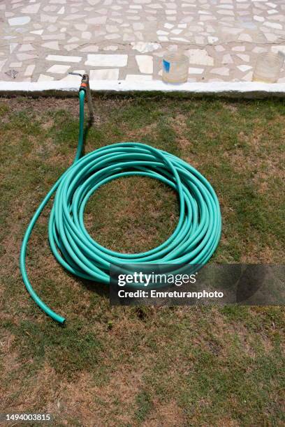 close up view of a coiled up garden hose on a sunny day. - water whorl grass stock pictures, royalty-free photos & images