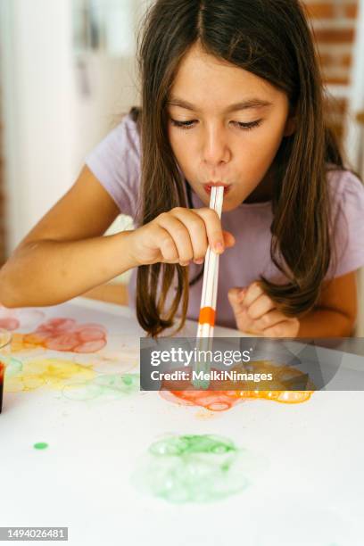 girl blowing bubbles with straw and painting the drawing on the paper - stro stockfoto's en -beelden