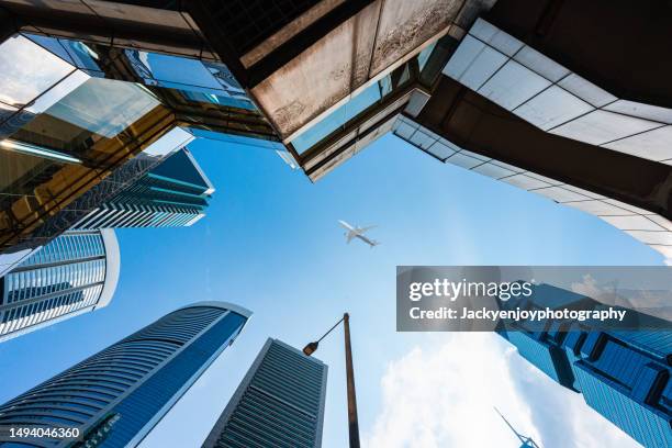 skyscrapers directly beneath a flying airplane - commercial aircraft flying stockfoto's en -beelden