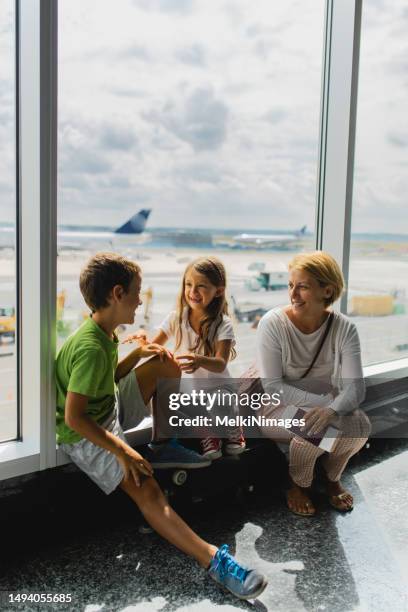 family talking and smiling  while waiting for their fly on the airport - airport sitting family stock pictures, royalty-free photos & images