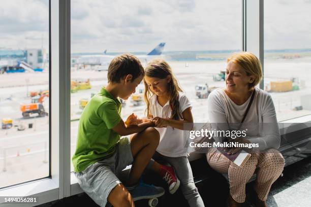 familie redet und lächelt, während sie auf ihren flug am flughafen wartet - german passports stock-fotos und bilder