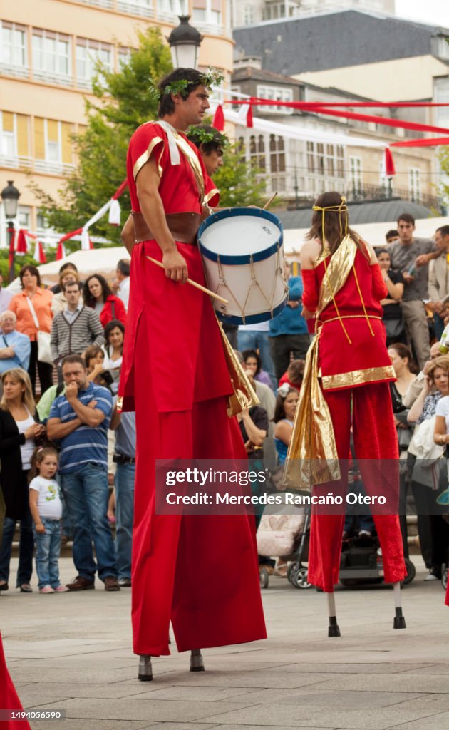 竹馬の上を歩く若いドラマー。歴史的な服。