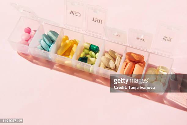 box for pills and capsules on pink background. pills organizer. - pilulier photos et images de collection