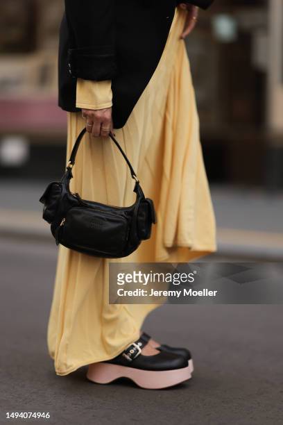 Karin Teigl wearing Jacquemus long cotton yellow pastell dress, Mugler x H&M black oversized blazer, MiuMiu Pocket black leather bag and AGL plateau...