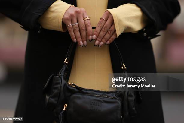 Karin Teigl wearing Jacquemus long cotton yellow pastell dress, Mugler x H&M black oversized blazer, MiuMiu Pocket black leather bag and AGL plateau...