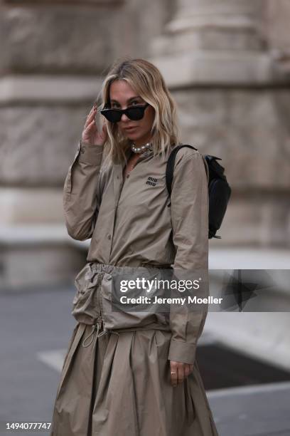 Karin Teigl wearing Miu Miu earth tones logo flannel, Miu Miu matching midi skirt, Miu Miu Pocket belt, Miu Miu Pocket black leather bag, Miu Miu...