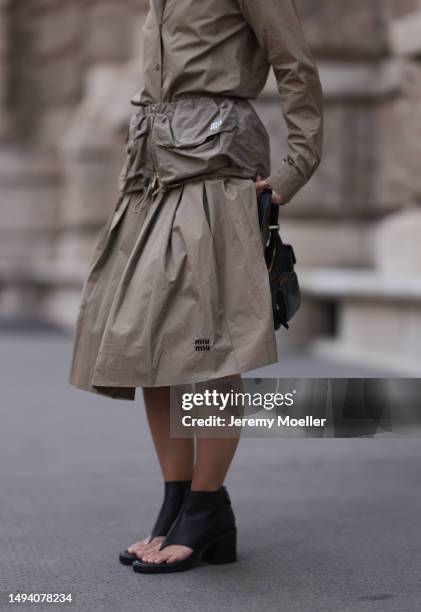 Karin Teigl wearing Miu Miu earth tones logo flannel, Miu Miu matching midi skirt, Miu Miu Pocket belt, Miu Miu Pocket black leather bag, Miu Miu...