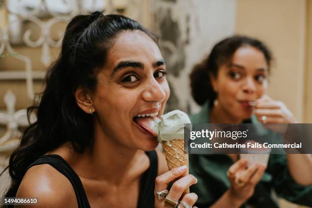 two woman sit on an outdoor stoop and enjoy ice-cream - freundinnen urlaub sommer eis stock-fotos und bilder