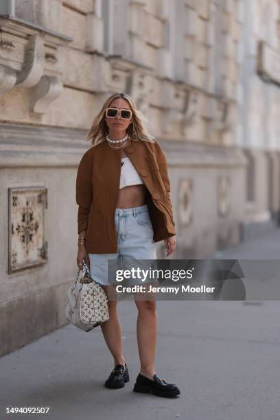 Karin Teigl wearing Gucci black leather loafer, Louis Vuitton beige brown speedy bag, Prada logo white linen logo bra top and Prada brown blazer...