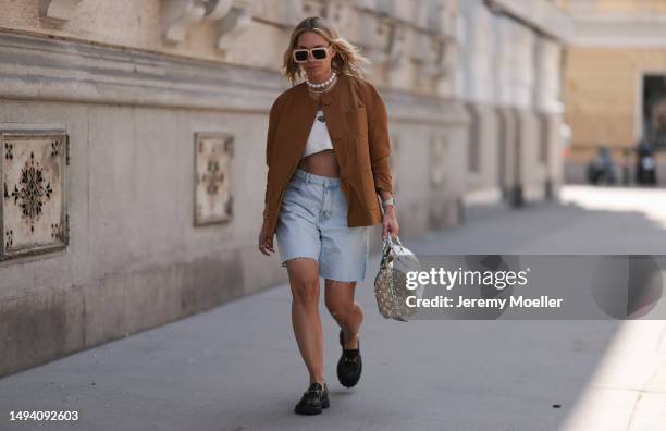 Karin Teigl wearing Gucci black leather loafer, Louis Vuitton beige brown speedy bag, Prada logo white linen logo bra top and Prada brown blazer...