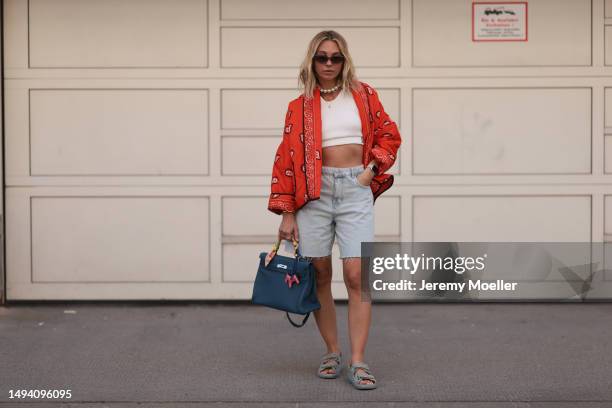 Karin Teigl wearing Valentino shades, Zara jeans shorts, CYK white cropped bra top, Hermes blue leather Kelly bag, Chanel denim sandals, Julia...