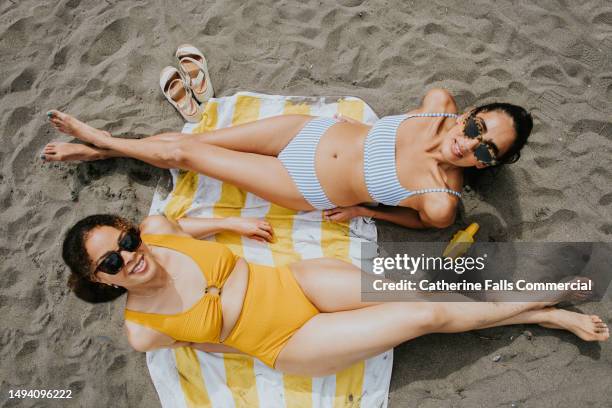 top down image of two beautiful young woman lying on a beach towel on the beach - baño-de-pies fotografías e imágenes de stock