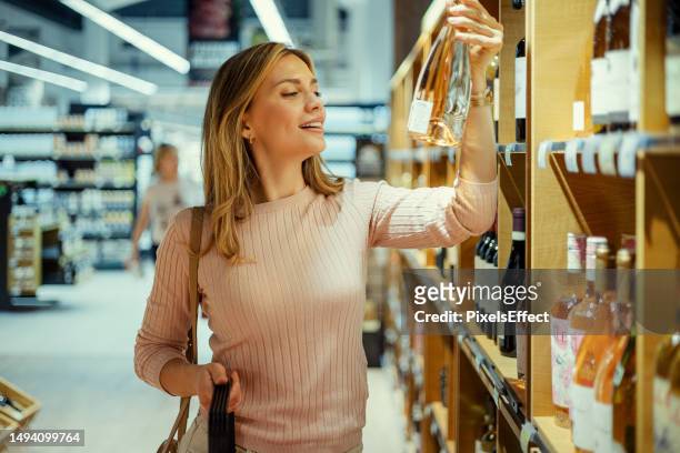 woman choosing wine bottle - choosing wine stock pictures, royalty-free photos & images