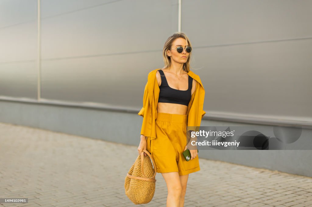 Mulher de negócios com smartphone em terno amarelo. Estilo de vida. Compras. Cabelos loiros. Saco
