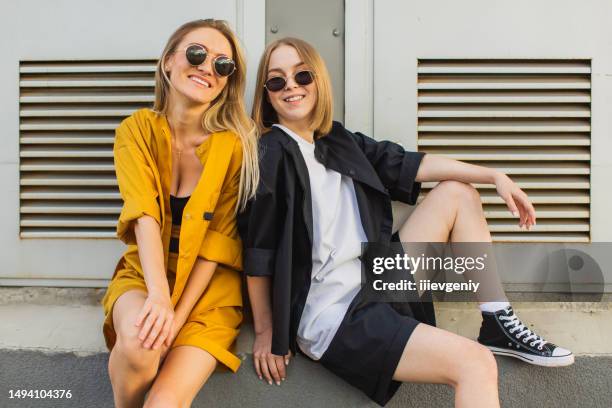 two young women in suit. lifestyle. blonde hair. youth culture. fashion - black suit sunglasses stock pictures, royalty-free photos & images