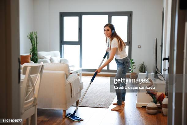 happy beautiful young women is cleaning the floor in the living room and have fun. - mopping floor stock pictures, royalty-free photos & images